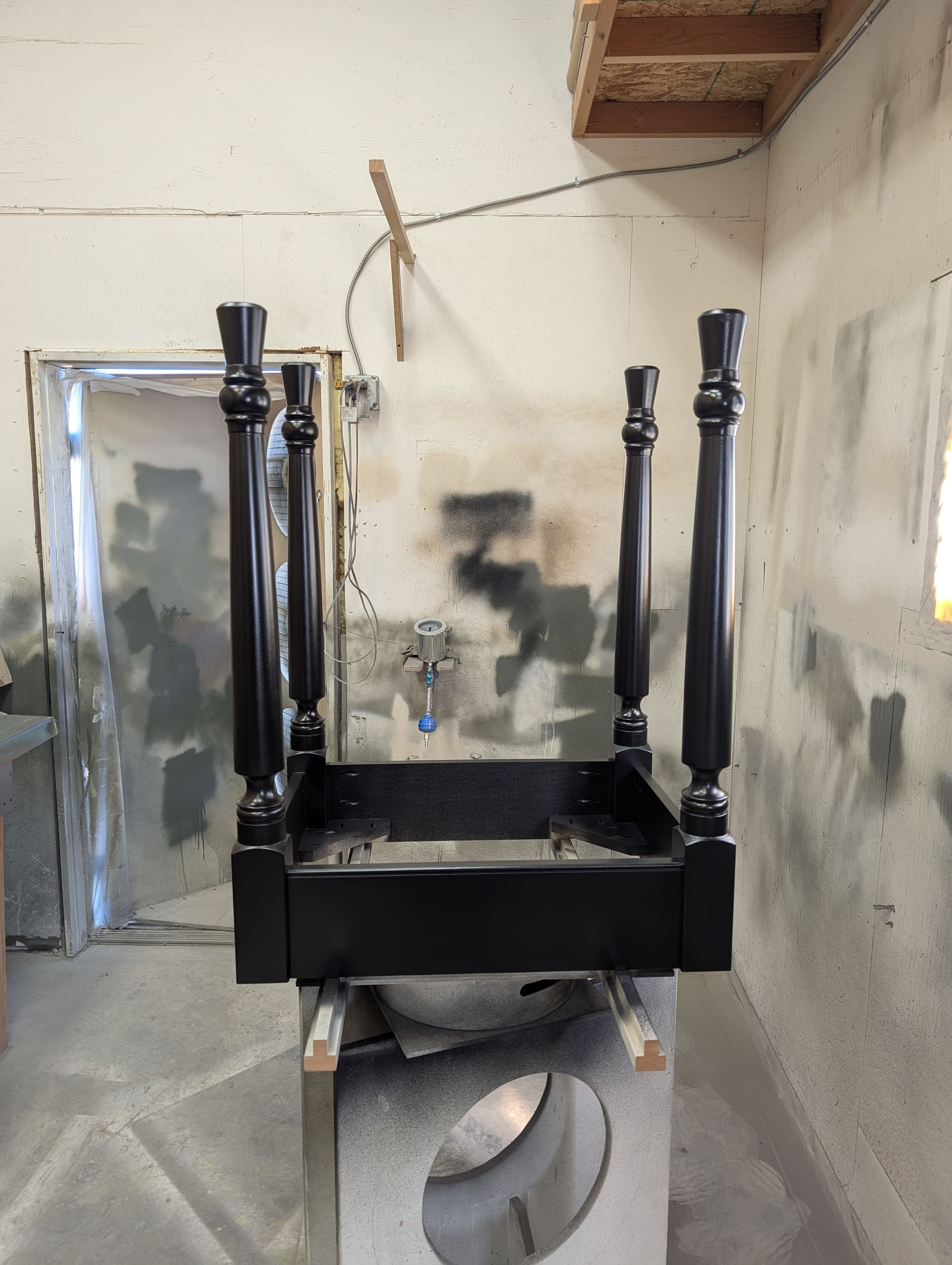 Black lacquered island base with turned legs curing in the spray booth