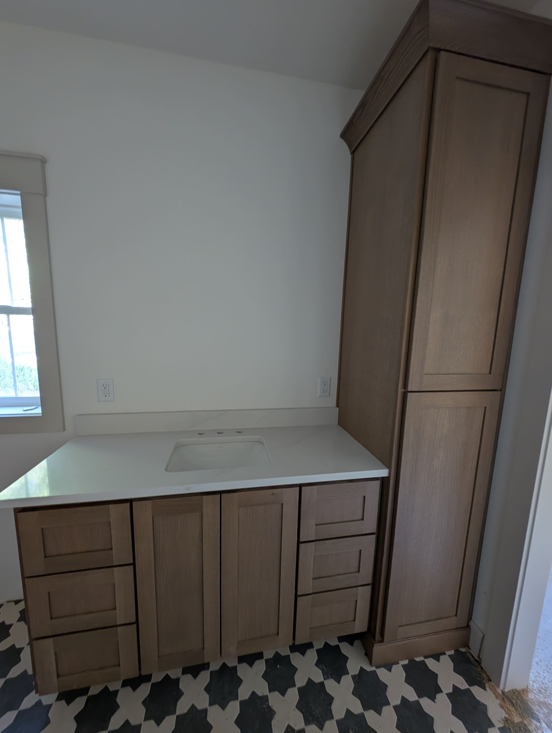 Custom vanity and floor-to-ceiling linen tower with matching quartz countertop