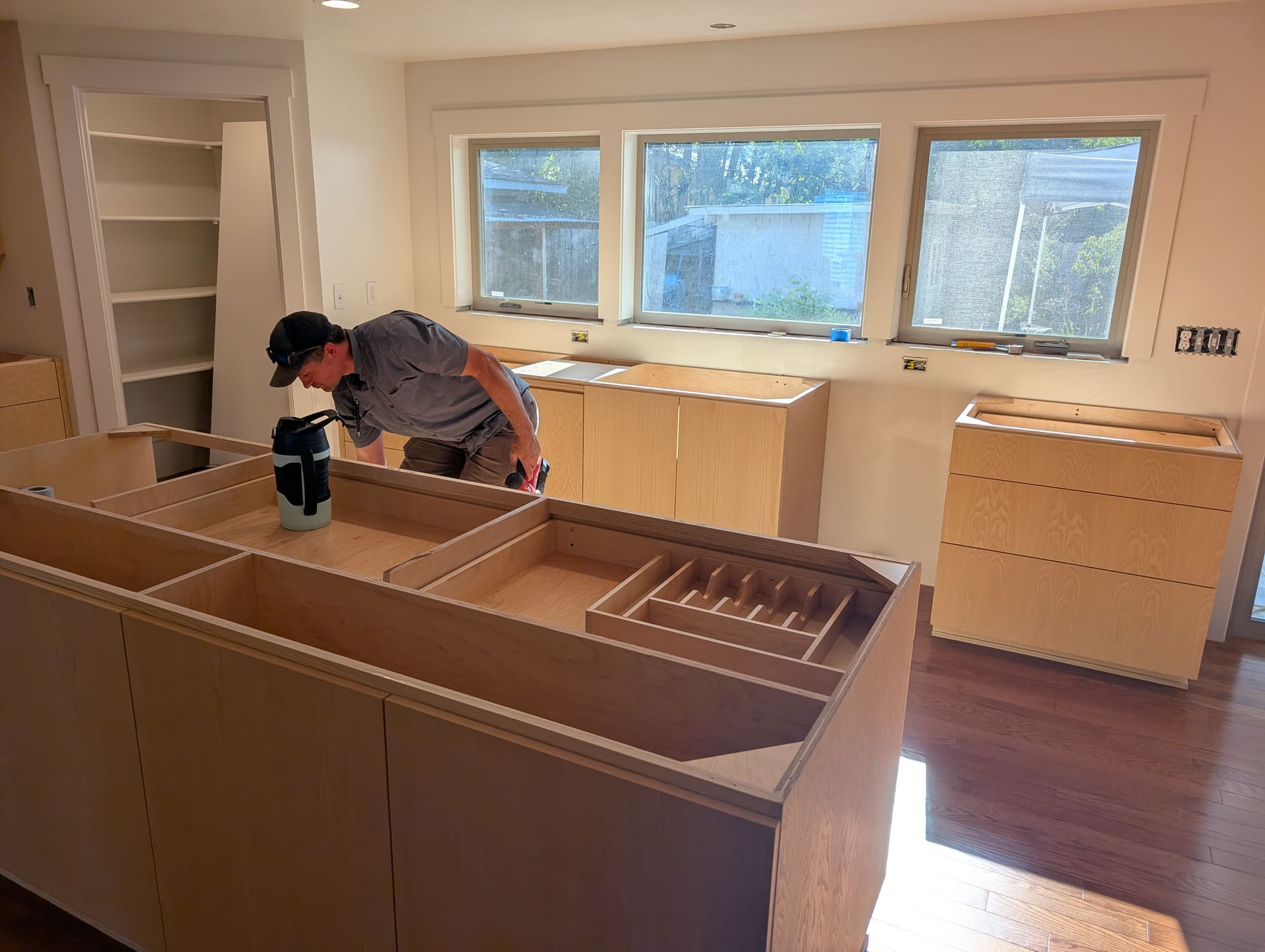 Craftsman fitting a frameless European kitchen island during installation, reviewing appliance layout and clearances