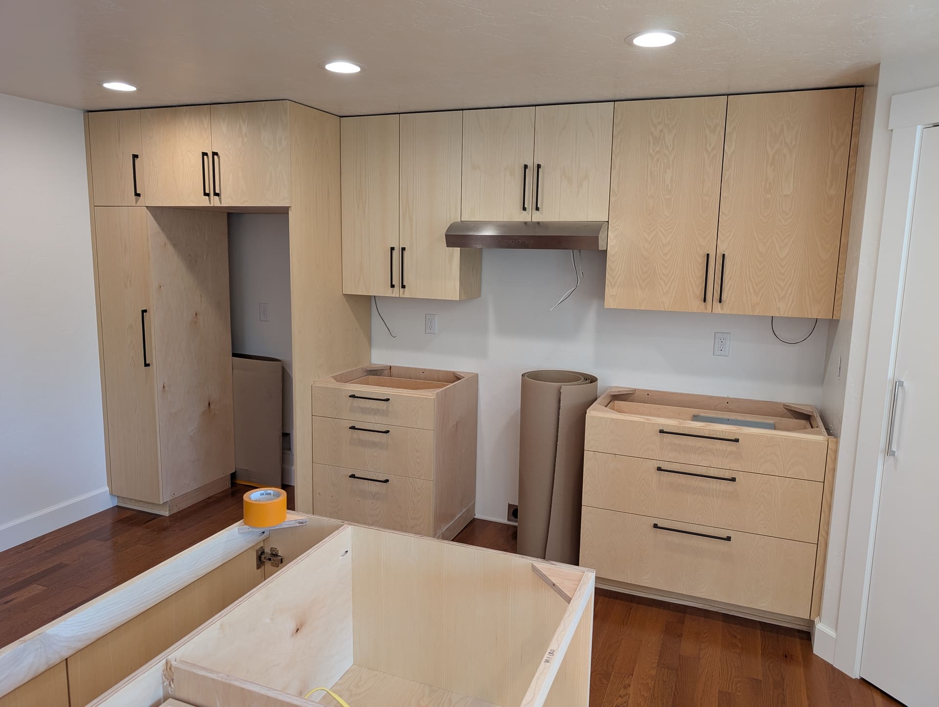 Modern frameless European kitchen cabinetry with black hardware and range hood